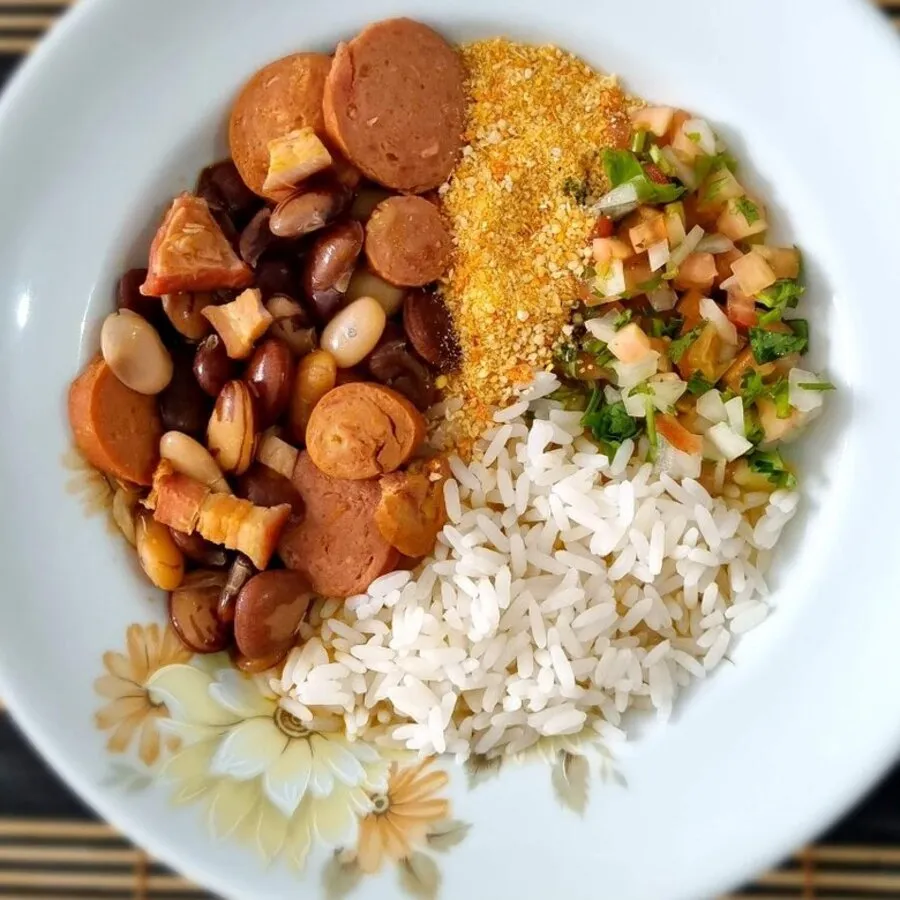 Prato com feijão, calabresa, farofa, arroz e vinagrete